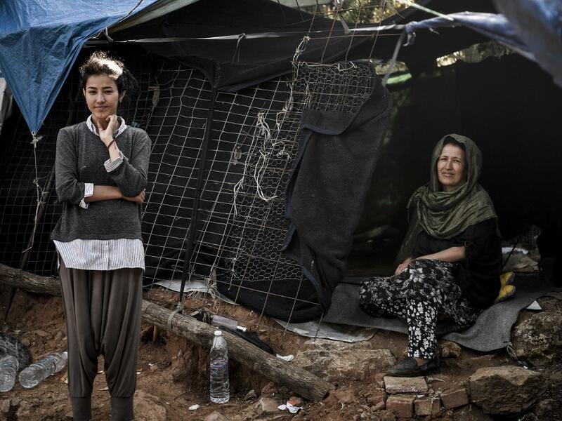 A mother and daughter pose in front of their makeshift shelter at the Samos refugee camp, just above the island's capital city of Vathy.  LOUISA GOULIAMAKI / AFP