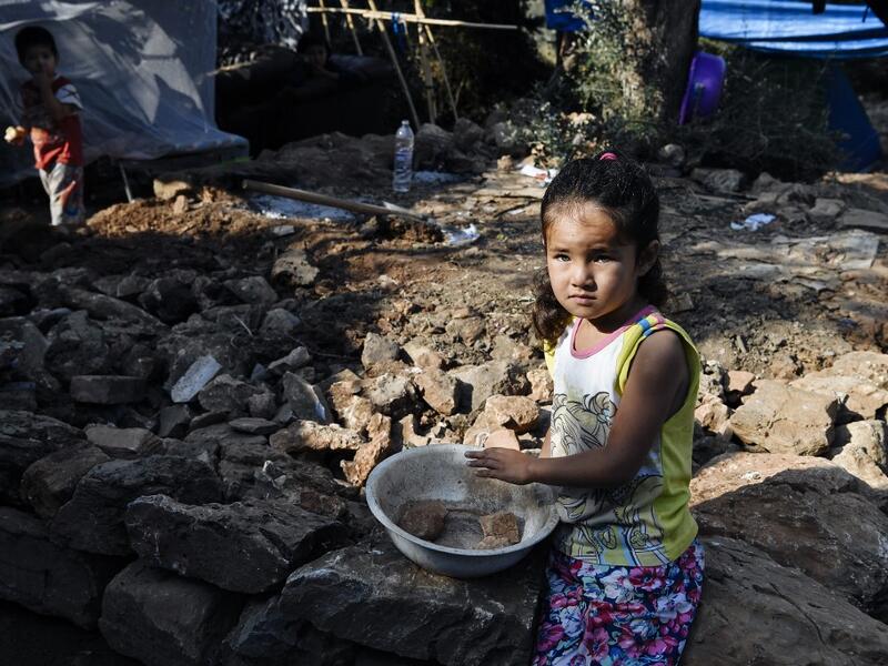 A girl gazes at the makeshift part of the Samos refugee camp, just above the island's capital city of Vathy.  LOUISA GOULIAMAKI / AFP
