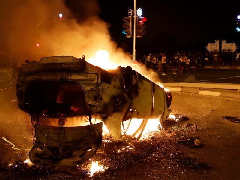 A burning and overturned police car blocks an entrance to the Israeli coastal city of Netanya , during a protest against the killing of Solomon Tekah, a young man of Ethiopian origin, who was killed by an off-duty police officer.  JACK GUEZ / AFP
