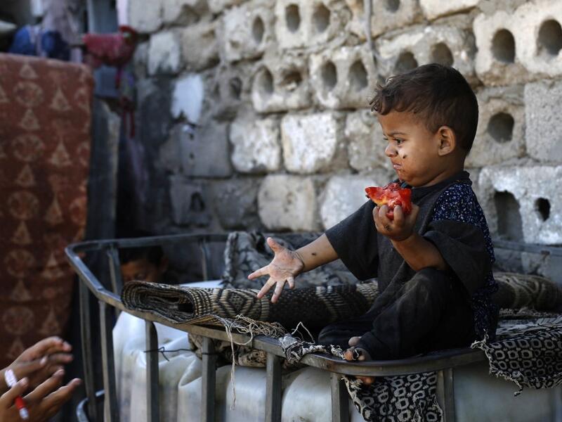 A Palestinian boy eats a tomato at an impoverished neighbourhood in Gaza City on July 4, 2019.  MOHAMMED ABED / AFP