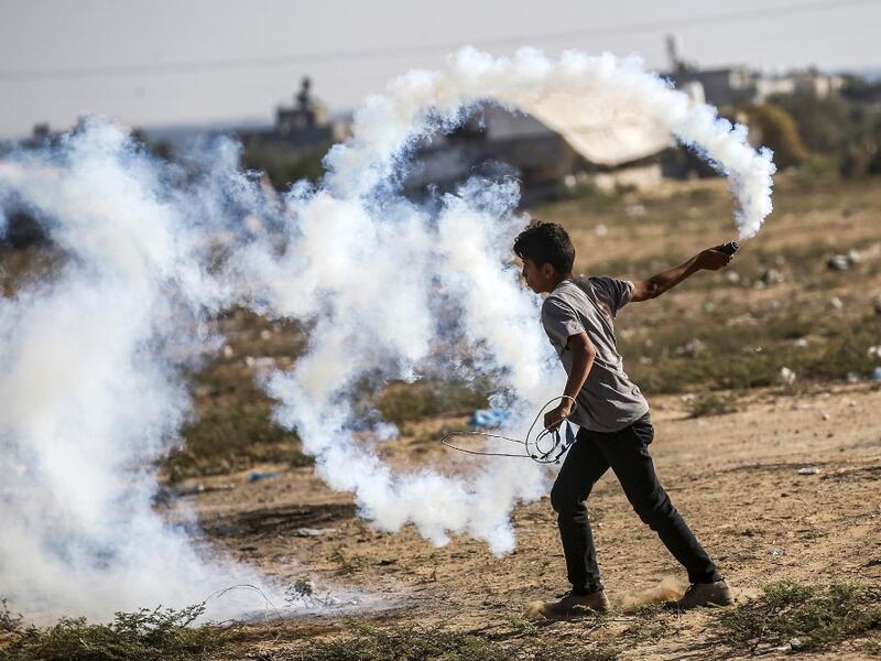 A Palestinian protester carries a tear gas canister to be thrown back at Israeli forces across the border during protests along the border with Israel east of Khan Yunis in the southern Gaza strip on July 5, 2019.  SAID KHATIB / AFP