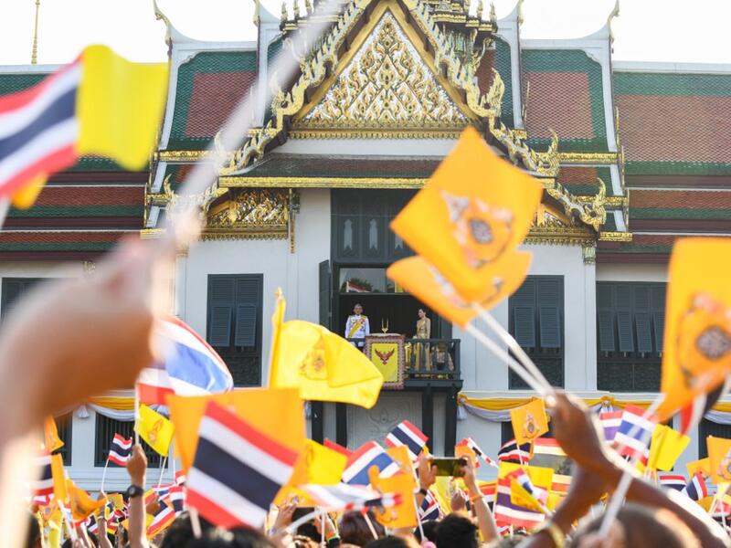 Thailand's King Maha Vajiralongkorn and Queen Suthida appear on the balcony of Suddhaisavarya Prasad Hall of the Grand Palace while people wave Thailand national flag and royal flag as they grant a public audience on the final day of his royal coronation in Bangkok on May 6, 2019.  Manan VATSYAYANA / AFP