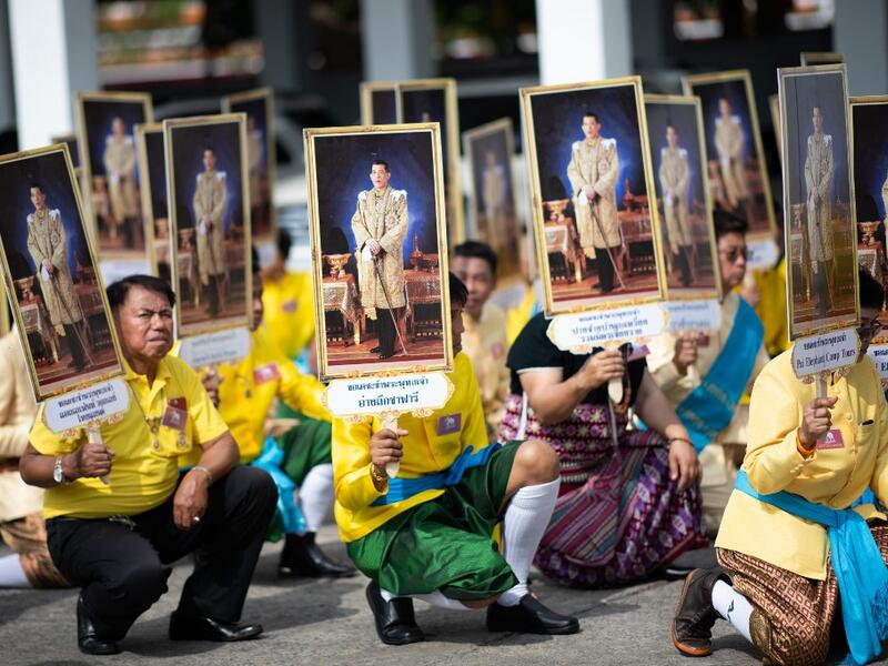 Well-wishers hold pictures of Thailand's King Maha Vajiralongkorn during a procession near the Grand Palace to pay their respects to the King in Bangkok on May 7, 2019.  Jewel SAMAD / AFP