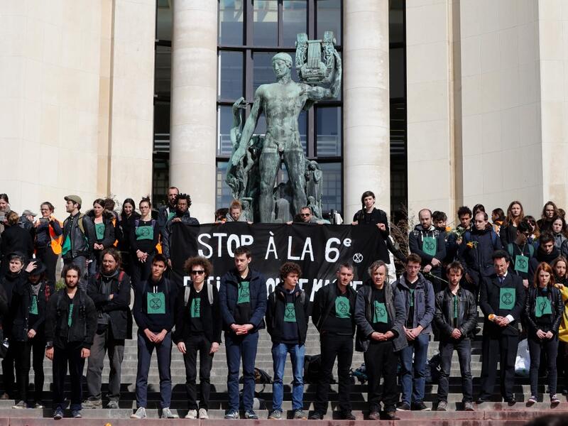 Members of the action group Extinction Rebellion (XR) hold a banner after spilling fake blood on the steps of the Trocadero esplanade during a demonstration to alert on the state of decline of biodiversity, on May 12, 2019 in Paris. FRANCOIS GUILLOT / AFP
