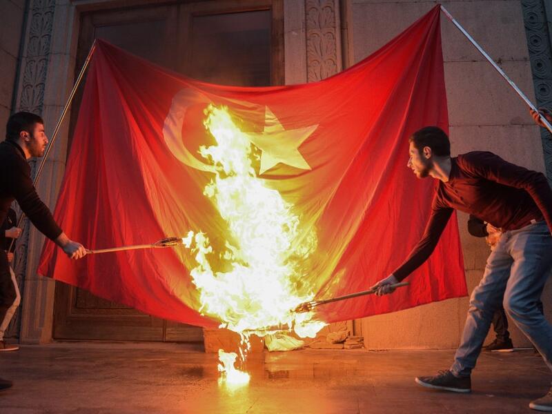 Men burn a Turkish flag ahead of a torchlight procession as they mark the anniversary of the killing of 1.5 million Armenians by Ottoman forces, Yerevan, April 23, 2019. KAREN MINASYAN / AFP