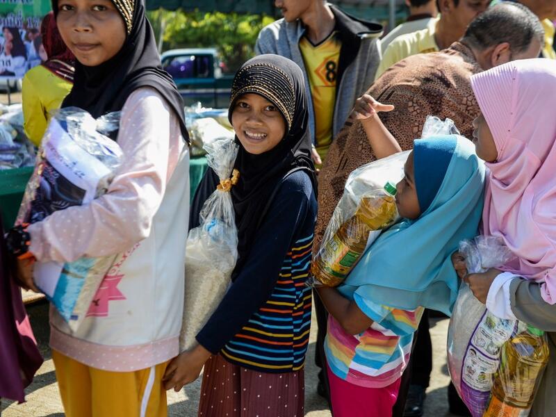 Thai Muslim girls carry bags of rice and food donated by the local government during a ceremony ahead of the Islamic holy month of Ramadan in the southern Thai province of Narathiwat on May 4, 2019.  Madaree TOHLALA / AFP