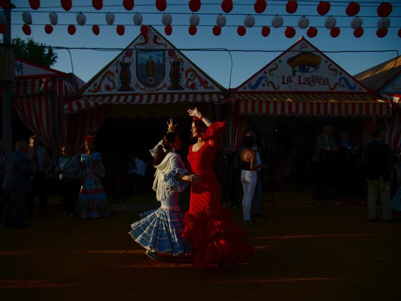 Women in traditional Sevillian dresses dance during the "Feria de Abril" (April Fair) festival in Seville on May 6, 2019. The fair dates back to 1847 when it was originally organized as a livestock fair but has turned into a week of flamenco dancing, music and bullfighting.  CRISTINA QUICLER / AFP