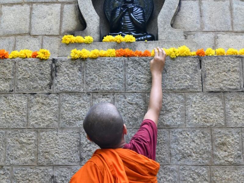 A young Buddhist monk decorates a stupa with flowers during "Vesak" or Buddha Purnima to commemorate the 2,563rd birth anniversary of the Buddha, at the Maha Bodhi Society in Bangalore on May 18, 2019. MANJUNATH KIRAN / AFP