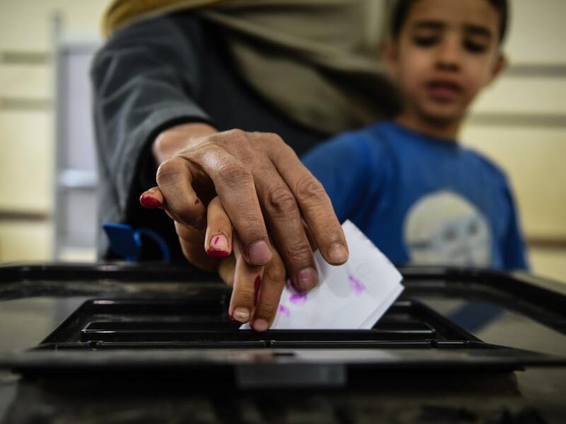 An man Egyptian casts his ballot with a child at a polling station during the third day of a referendum on constitutional amendments, at a school in shamma village in the northern Nile delta province of Menoufia, on April 22, 2019.  Mohamed el-Shahed / AFP