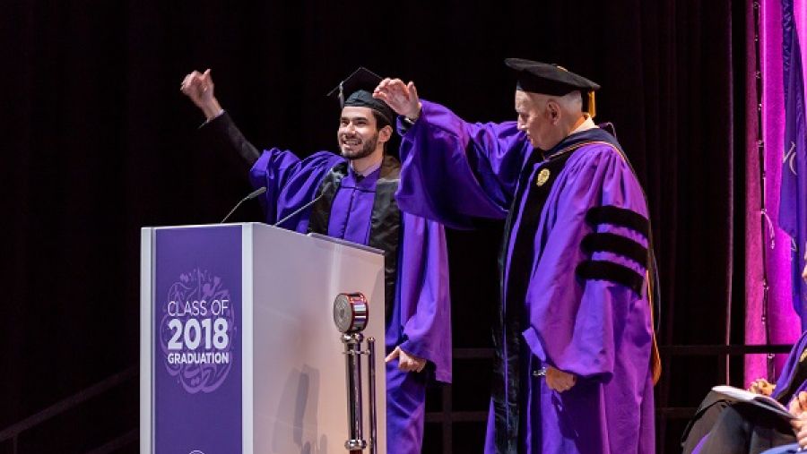 فؤاد حسن، المتحدث باسم طلاب الجامعة في حفل التخرج  وإيفيرت دينيس، عميد جامعة نورثويسترن في قطر  يؤدون هتاف الجامعة.