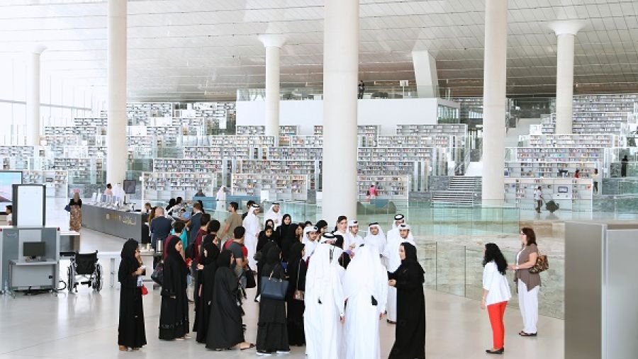 مجموعة من الطلاب يتحدثون مع موظفي مكتبة قطر الوطنية أثناء قيامهم بجولة في مرافق المبنى الجديد