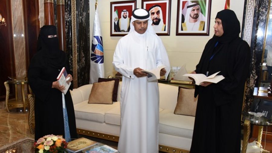 أحمد محبوب يطلع على إحدى الكتب التي ستوزع خلال الحملة من شيخة الغافري وشيخه مسعود 