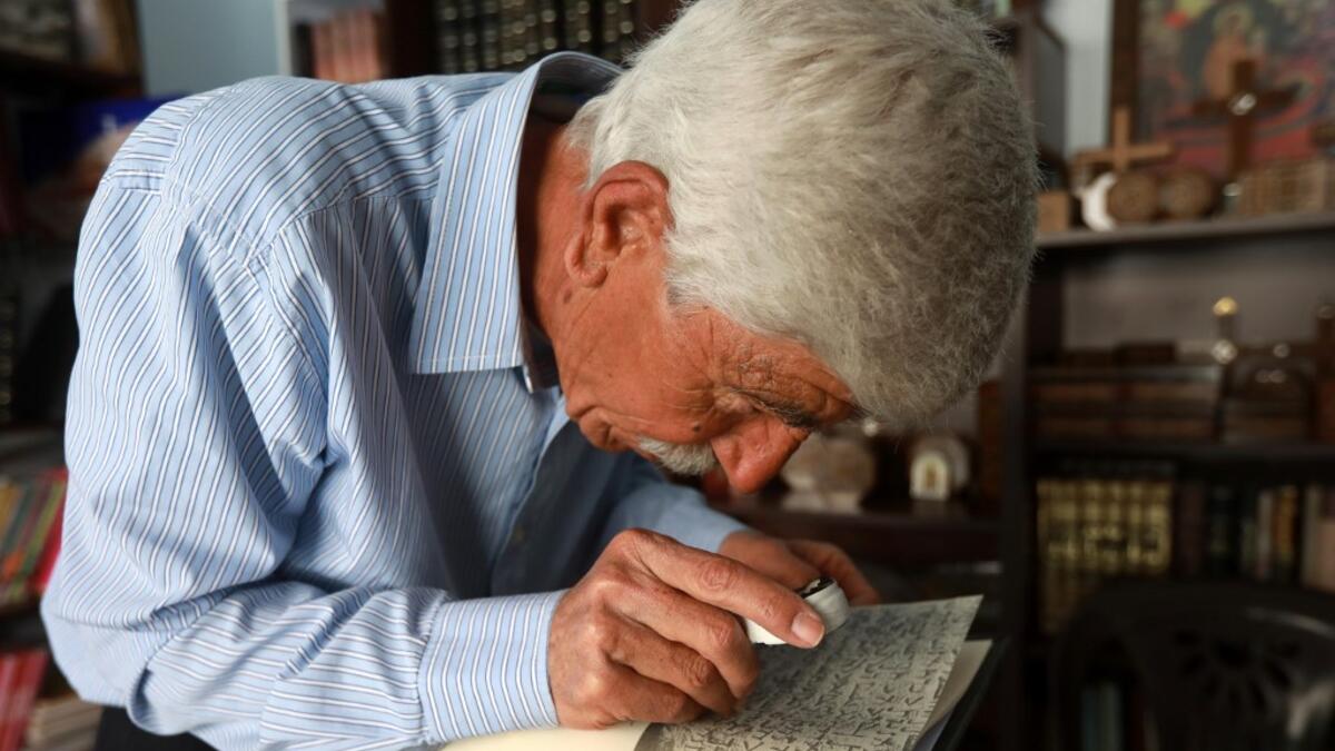 George Zaarour, a specialist in the Aramaic language, uses a magnifying glass to decipher Aramaic script in the Syrian mountain village of Maalula, in the Damascus region on May 13, 2019. LOUAI BESHARA / AFP
