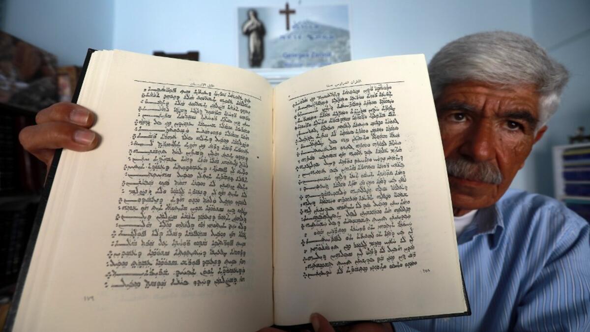 George Zaarour, a specialist in the Aramaic language, shows a book written in the Aramaic script in the Syrian mountain village of Maalula, in the Damascus region on May 13, 2019. LOUAI BESHARA / AFP