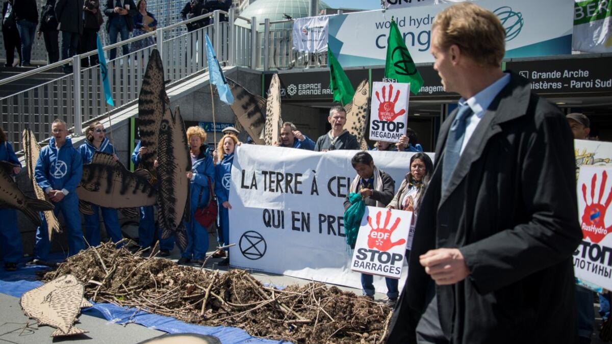 A man walks past activists of 'Extinction Rebellion' (XR) and NGO 'Planete Amazone' as they stage a protest against large hydroelectric dams in front of the Grande Arche de La Defense, in Puteaux, northwest of Paris, on May 14, 2019. AFP