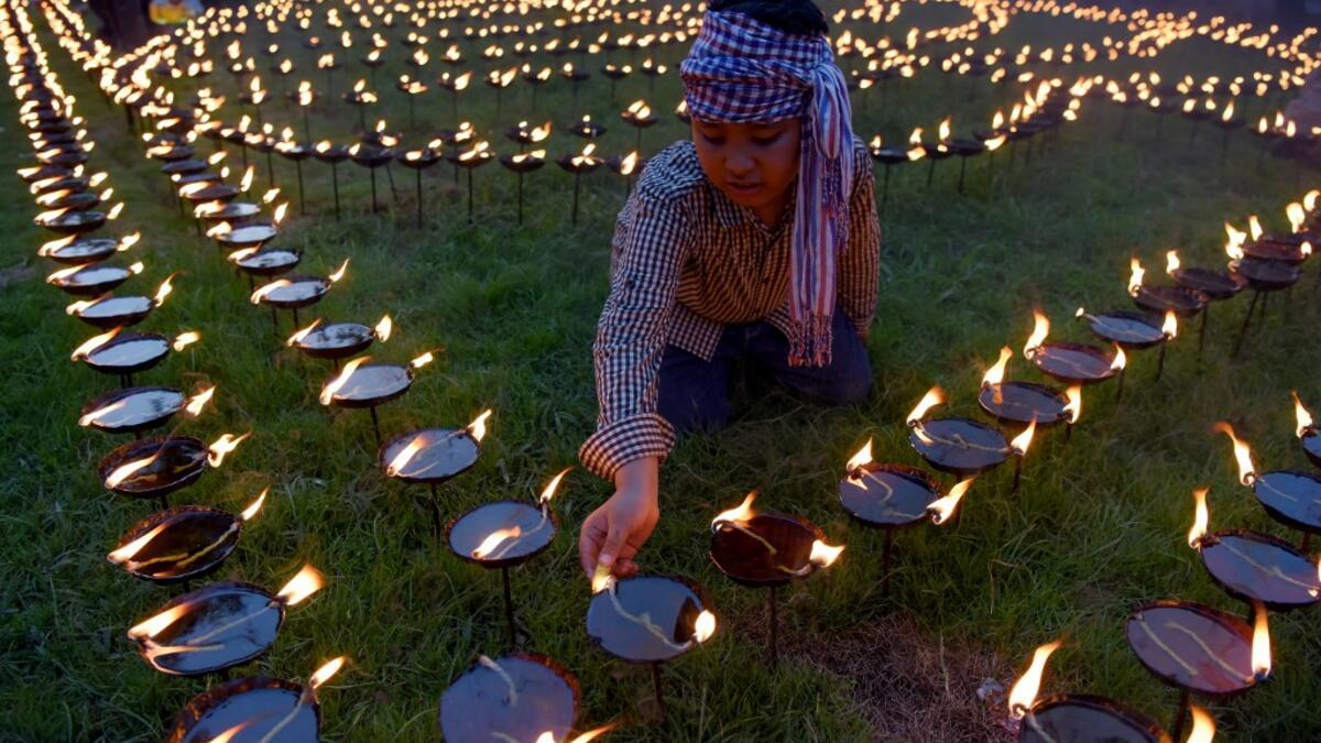 A Cambodian boy lights candles during the Visak Bochea Buddhist celebration at a pagoda in Phnom Penh on May 18, 2019. TANG CHHIN Sothy / AFP