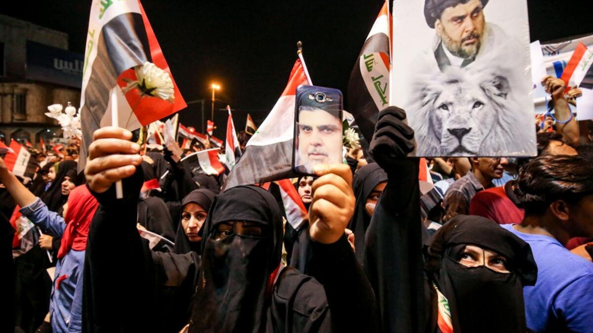 Iraqi followers of Shiite Muslim cleric Moqtada al-Sadr wave national flags and raise protest signs as they demonstrate in the capital Baghdad's central Tahrir Square late on May 24, 2019, against involvement in any conflict between Iran and the United States.  AHMAD AL-RUBAYE / AFP