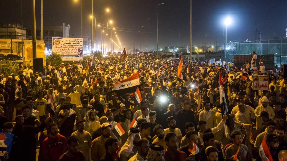 Iraqi followers of Shiite Muslim cleric Moqtada al-Sadr wave national flags and raise protest signs as they demonstrate in the southern city of Basra on May 24, 2019, against involvement in any conflict between Iran and the United States.  Hussein FALEH / AFP