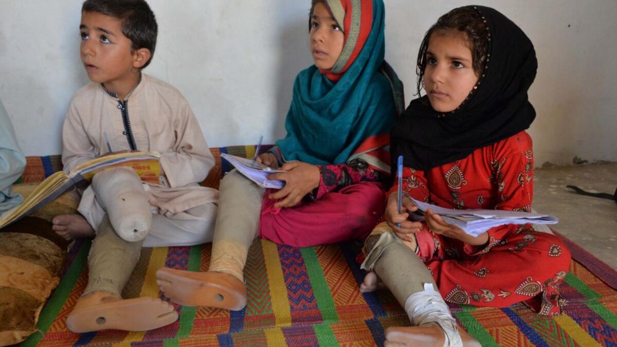 In this photograph taken on May 14, 2019, Hamisha Gul’s grandchildren, who lost their legs following unexploded rocket explosion, attend and study at a class in their house in Khogyani district of Nangarhar province. NOORULLAH SHIRZADA / AFP