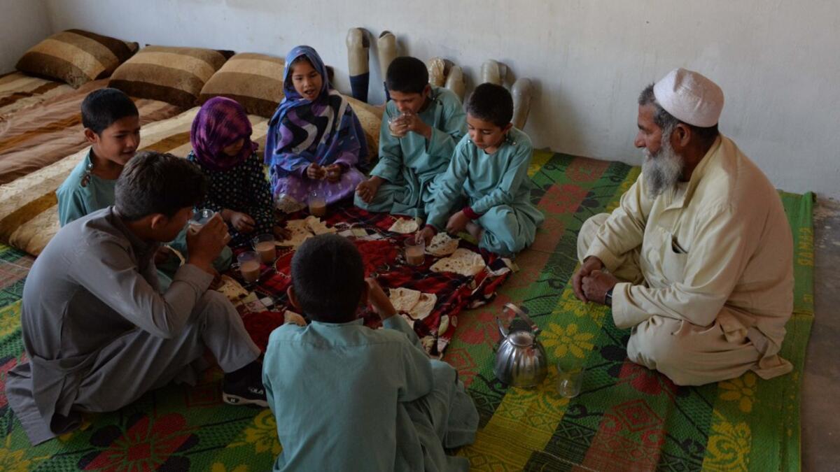 In this photograph taken on May 3, 2019, Afghan man Hamisha Gul 65, looks as his disabled children eat breakfast in their house in the Khogyani district of Nangarhar province. NOORULLAH SHIRZADA / AFP
