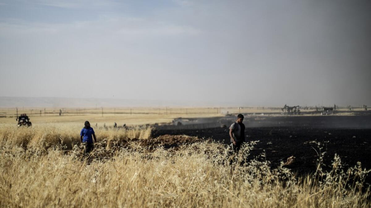 People battle a blaze next to an oil well in an agricultural field in the town of al-Qahtaniyah, in the Hasakeh province near the Syrian-Turkish border on June 10, 2019. Fires have erupted in various parts of Syria in recent weeks, with all sides blaming each other for starting them. Delil souleiman / AFP