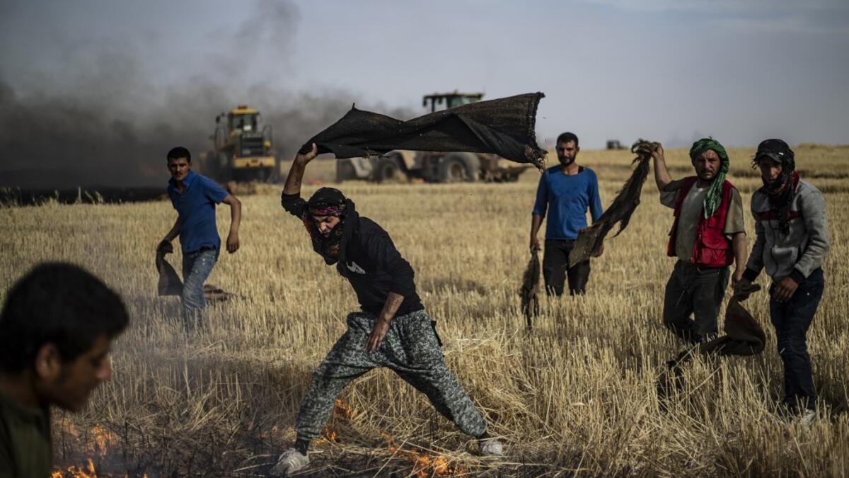 People battle a blaze next to an oil well in an agricultural field in the town of al-Qahtaniyah, in the Hasakeh province near the Syrian-Turkish border on June 10, 2019. Fires have erupted in various parts of Syria in recent weeks, with all sides blaming each other for starting them. Delil souleiman / AFP