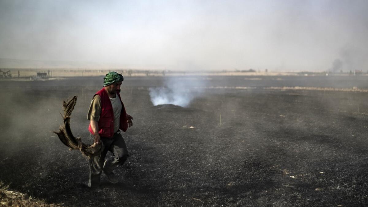 People battle a blaze next to an oil well in an agricultural field in the town of al-Qahtaniyah, in the Hasakeh province near the Syrian-Turkish border on June 10, 2019. Fires have erupted in various parts of Syria in recent weeks, with all sides blaming each other for starting them. Delil souleiman / AFP