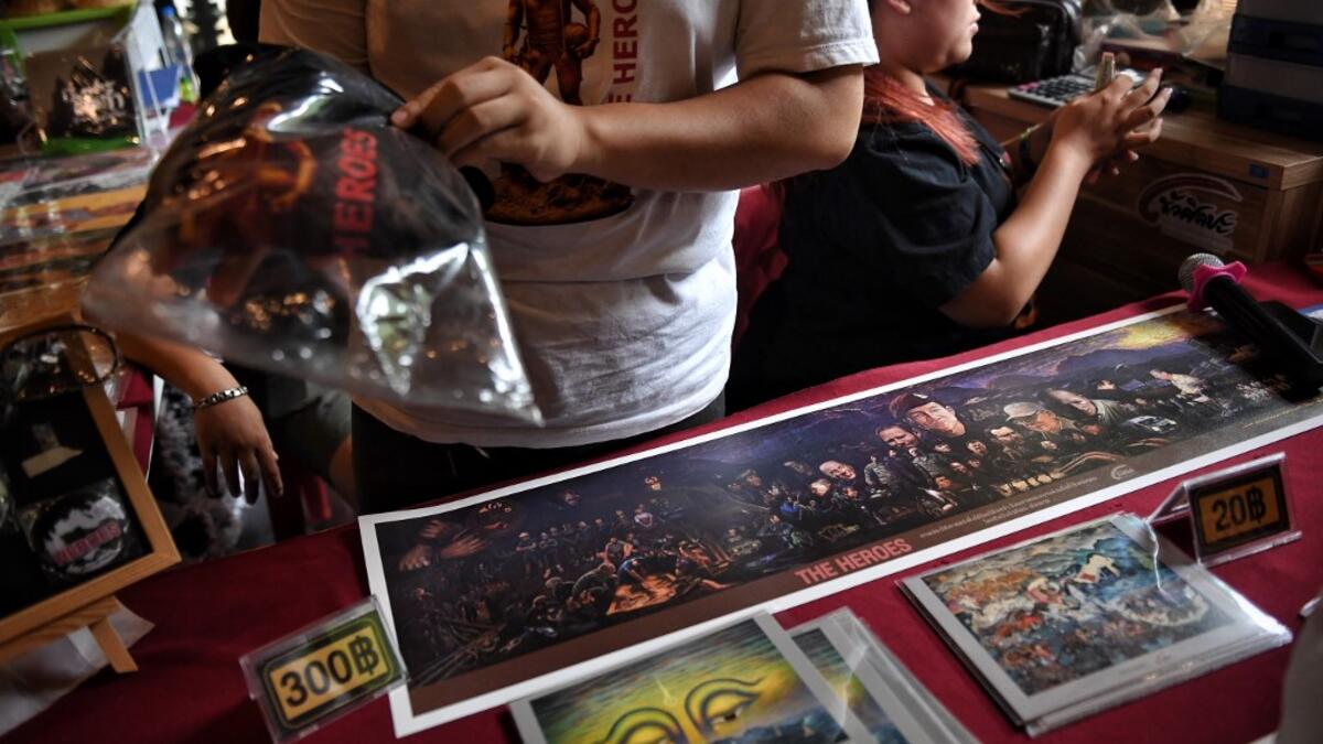 This picture taken on June 13, 2019 shows vendors selling memorabilia, illustrating the rescue of the 12 boys from the "Wild Boars" football team and their coach after they were trapped in the Tham Laung cave last year, at the cave's visitor centre in the Mae Sai district of Chiang Rai province. Lillian SUWANRUMPHA / AFP