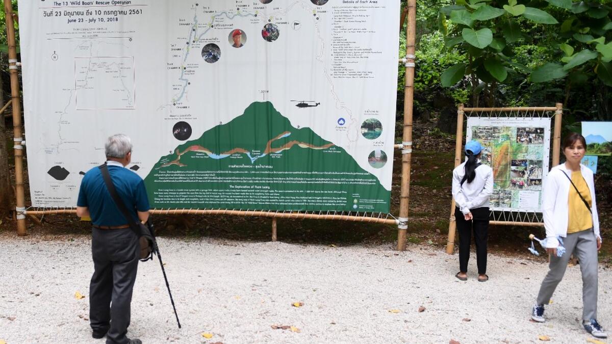 Tourists snap selfies by a bronze statue of the diver who died trying to save the 'Wild Boar' footballers from a flooded cave, while momentos from their rescue fly off the shelves -- scooped up by the 1.3 million people who have descended on a once serene mountainside in northern Thailand. Lillian SUWANRUMPHA / AFP
