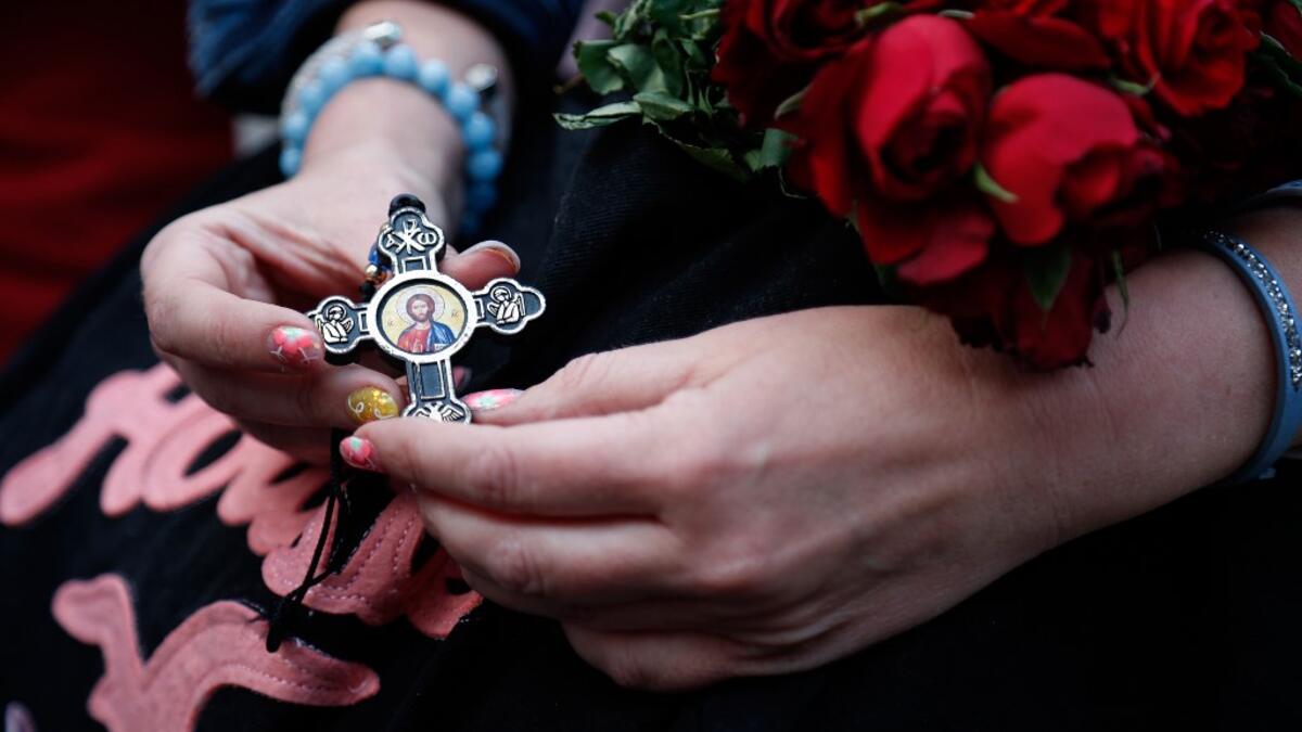 A woman holds a cross and roses as the first mass is held at the Notre-Dames de Paris Cathedral following the destructive April 15 fire, in Paris on June 15, 2019. Zakaria ABDELKAFI / AFP