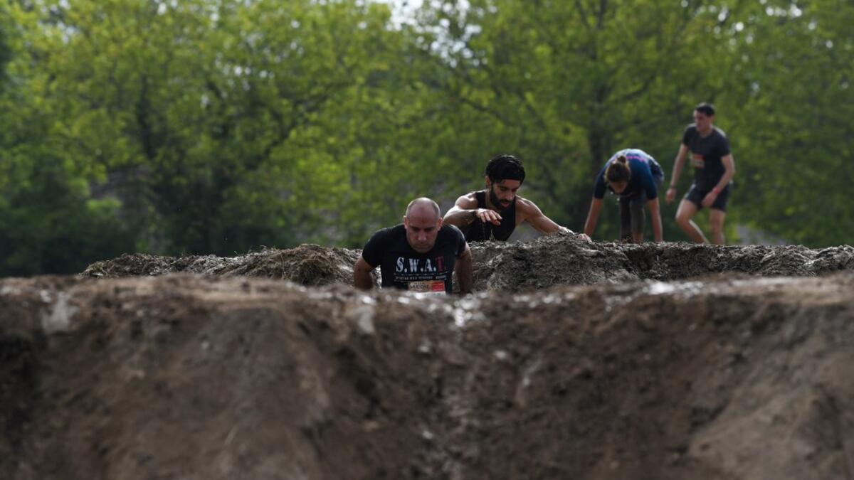 Runners cross an obstacle as they take part in the Mud Day, a 13km race with obstacles in Beynes, near Paris on June 16, 2019.  ALAIN JOCARD / AFP