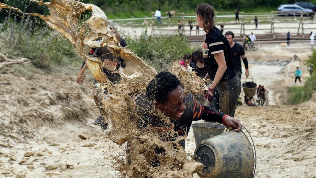 Mud is thrown at runners as they take part in the Mud Day, a 13km race with obstacles in Beynes, near Paris on June 16, 2019.  ALAIN JOCARD / AFP
