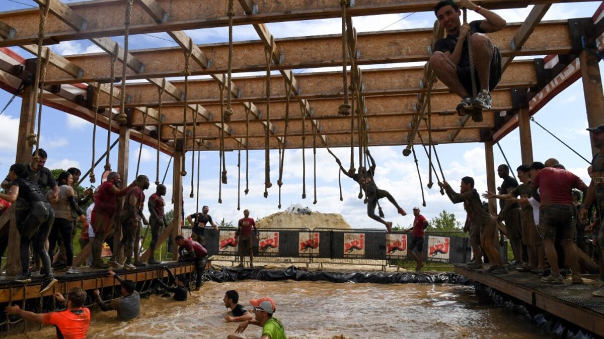 Runners cross an obstacle as they take part in the Mud Day, a 13km race with obstacles in Beynes, near Paris on June 16, 2019.  ALAIN JOCARD / AFP