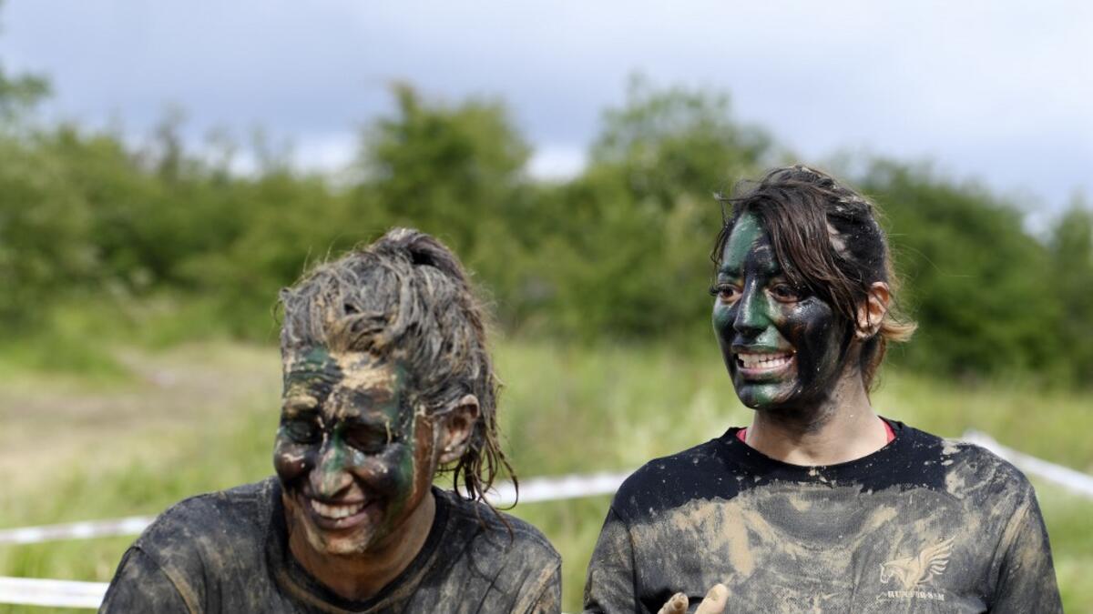 Runners wearing camouflage face paint react as they takes part in the Mud Day, a 13km race with obstacles in Beynes, near Paris on June 16, 2019.  ALAIN JOCARD / AFP