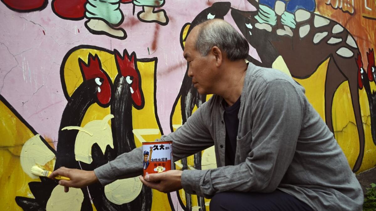 This picture taken on May 21, 2019 shows Hakka graffiti artist Wu Tsun-hsien painting a wall in the Taiwanese village of Ruan Chiao. Nestled in the mist-covered foothills of Taiwan's central mountain range, Ruan Chiao village is virtually devoid of young people, but artist Wu Tsun-hsien is coaxing the Instagram generation back by transforming local homes into a canvas of colour. Sam YEH / AFP