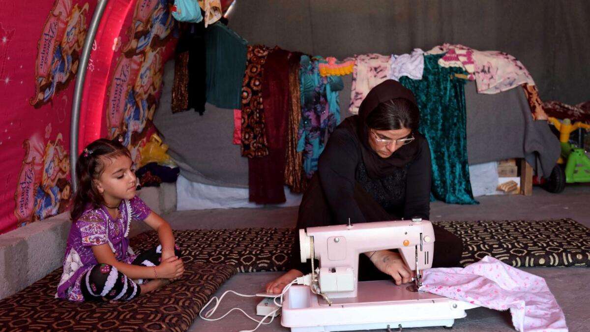 Iraq's Yazidi survivor Layleh Shemmo sews inside her tent in the Khonke camp for displaced persons in northwestern Iraq on June 24, 2019. Working in the Khonke displacement camp in northwest Iraq, Shemmo glances down at the name tattooed on her left hand: Kero, her husband, still missing five years after the Islamic State group rampaged across the Sinjar region. At the time, IS killed Yazidi men en masse, took boys as child soldiers and sold women as "sex slaves," with survivors streaming into shabby displa