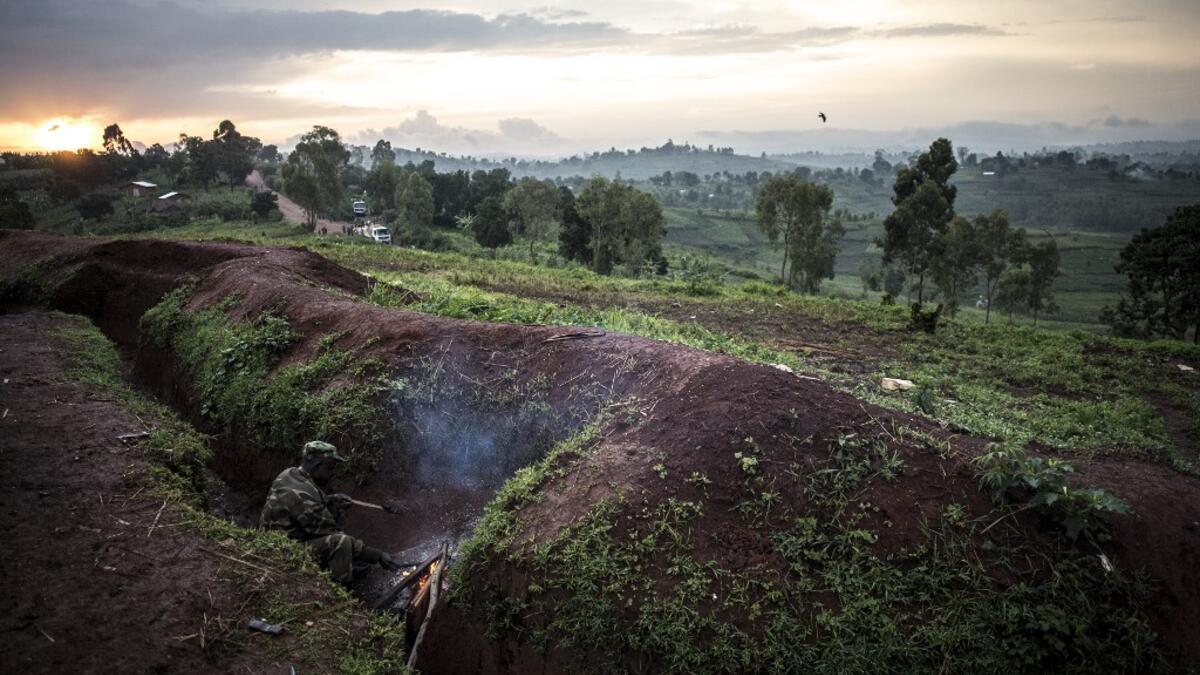 A soldier of the Armed Forces of the Democratic Republic of the Congo (FARDC) warms himself by the fire inside a base on July 4, 2019 in Djugu, eastern DR Congo. John WESSELS / AFP