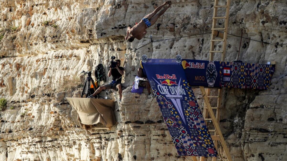 A cliff diver jumps from a platform on the landmark Raouche sea rock off the coast of the Lebanese capital Beirut on July 14, 2019, during the men's 2019 Red Bull Cliff Diving World Series.  ANWAR AMRO / AA / AFP