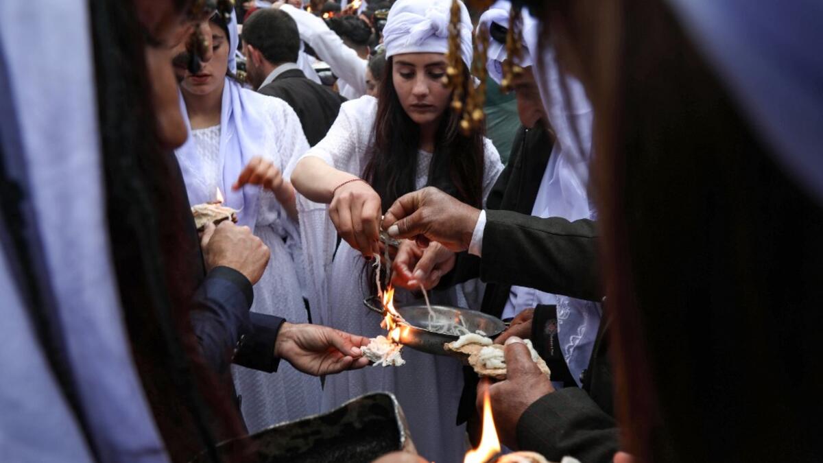 Iraqi Yazidi women light candles outside the Temple of Lalish, in a valley near the Kurdish city of Dohuk about 430 kilometres northwest of the capital Baghdad, on April 16, 2019, during a ceremony marking the Yazidi New Year. Of the 550,000 Yazidis in Iraq before the Islamic State (IS) group invaded their region in 2014, around 100,000 have emigrated abroad and 360,000 remain internally displaced. Roughly 3,300 Yazidis have returned from IS captivity in the last five years, only 10 percent of them men. SAF