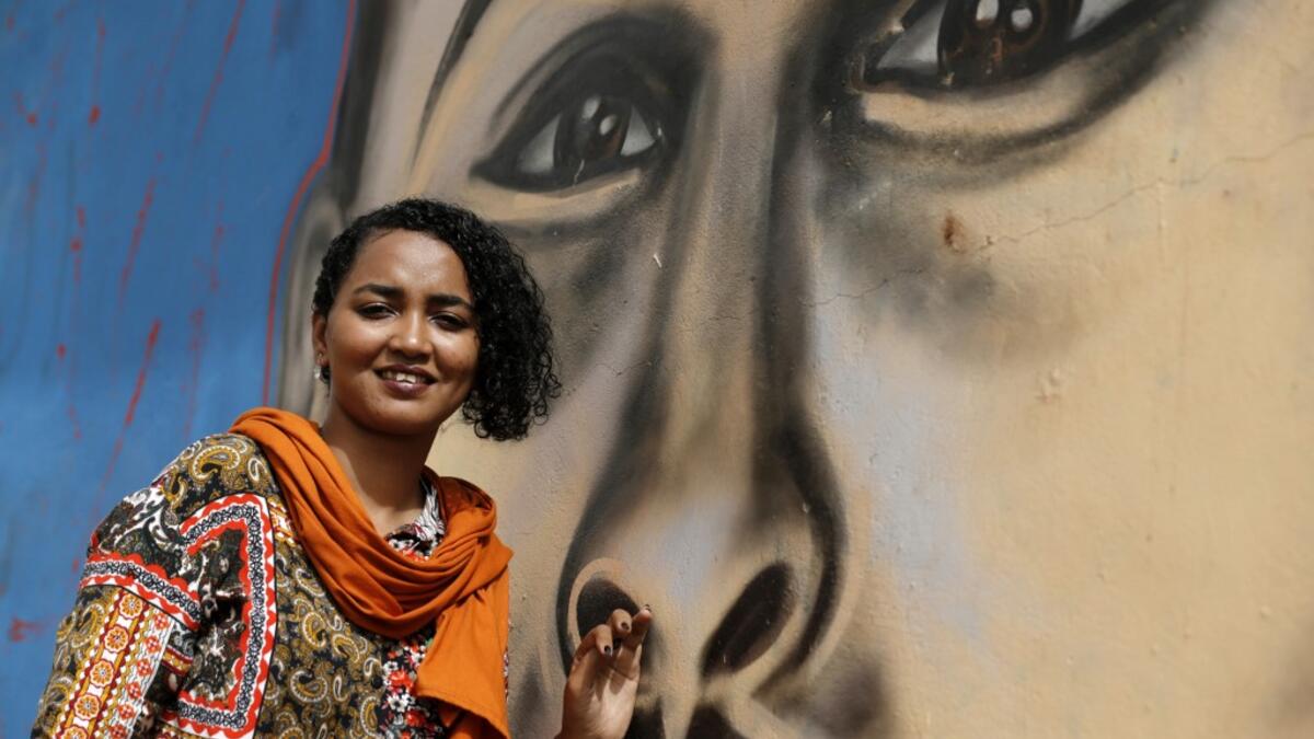 Sudanese activist Eythar Gubara, is pictured in front of a mural painting of Mohamed Mattar, on the wall of a youth club in Bahri in the capital Khartoum's northern district on July 21, 2019.  ASHRAF SHAZLY / AFP