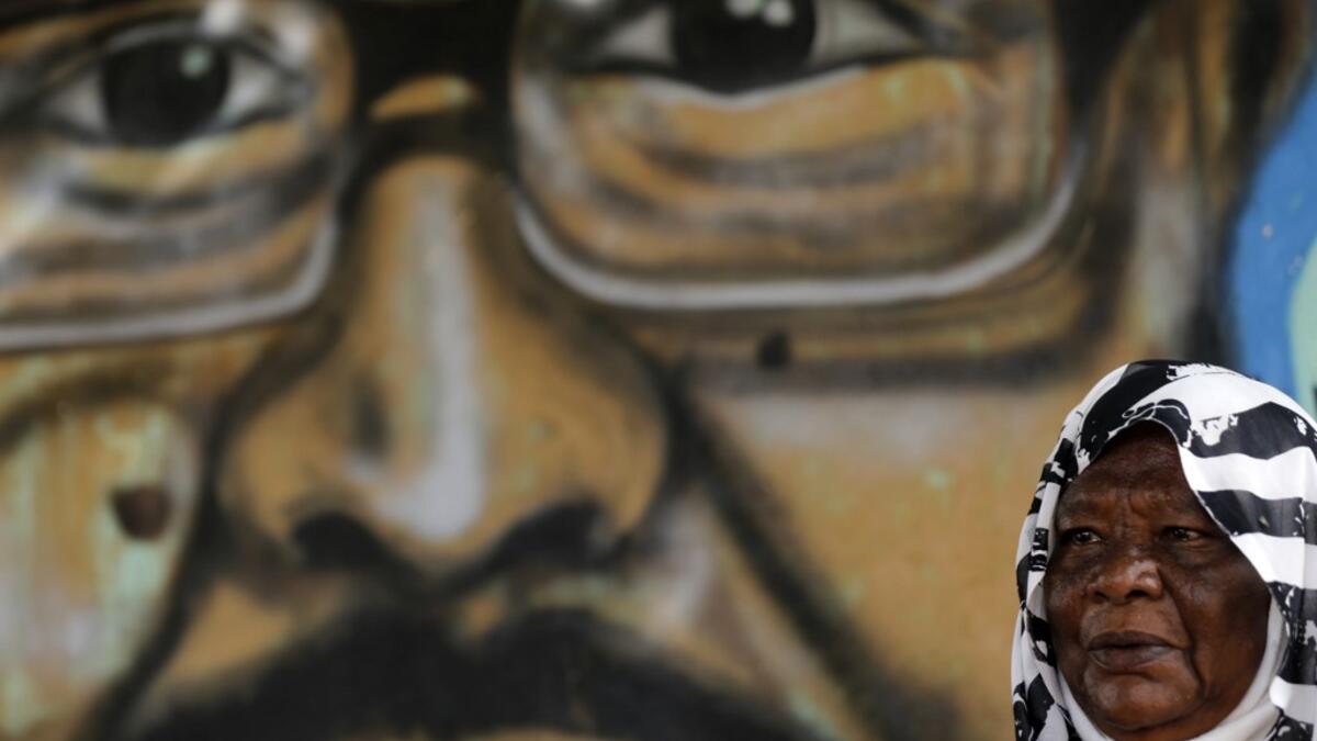 Maiyssa Omar, the mother of Walid Abdelrahim sits in front of the mural painting of her son, ornating the family home in the Sudanese capital Khartoum on July 21, 2019.  ASHRAF SHAZLY / AFP