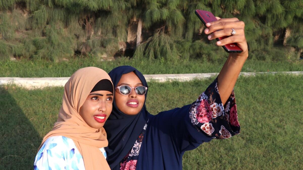 Rahma Abdullahi Mohamud (R) and Hani Hussein take selfies pictures with a mobile phone, after buying clothes designed by fashiondesigner Muna Mohamed Abdullahi, at Peace Garden in Mogadishu, Somalia. ABDI HAJJI HUSSEIN / AFP