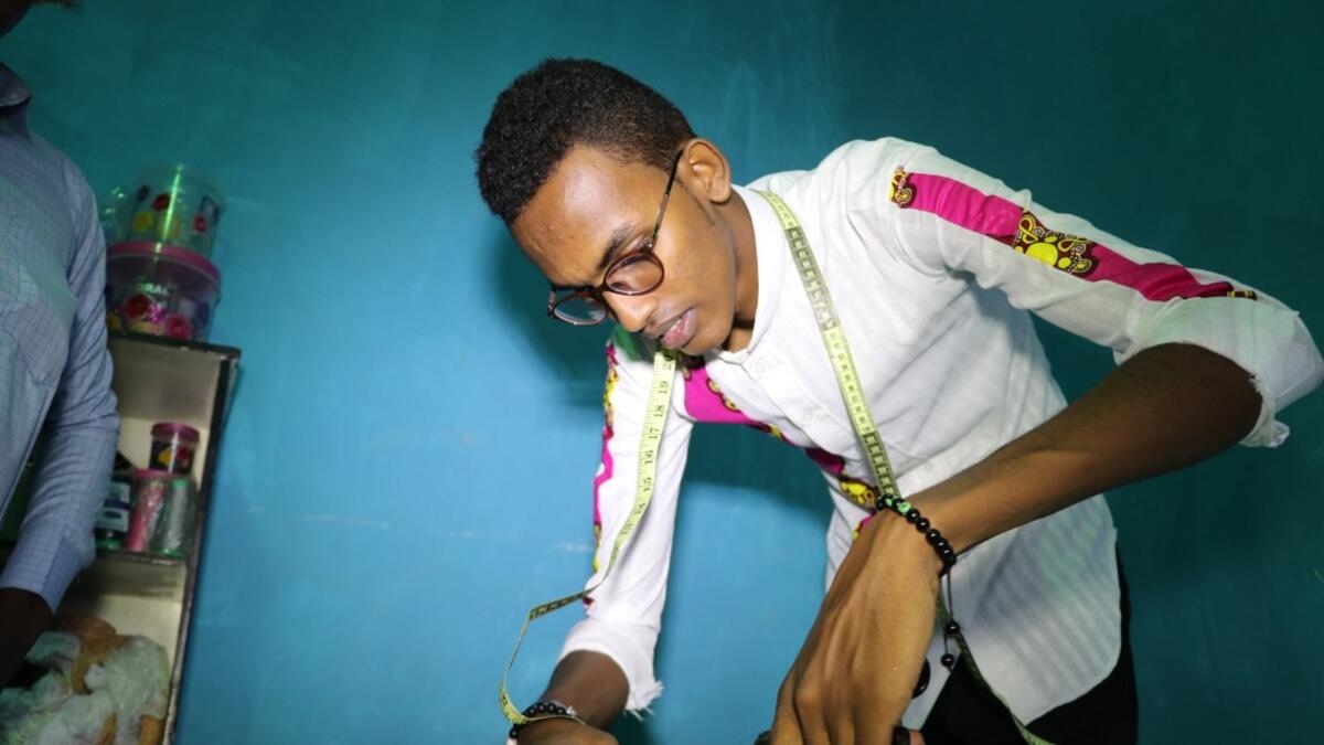 Abdishakur Abdirahman Adam, 19 years old, secondary school student and fashion designer for women and men, cuts fabrics, on November 4, 2018, in Mogadishu. Abdi HAJJI HUSSEIN / AFP