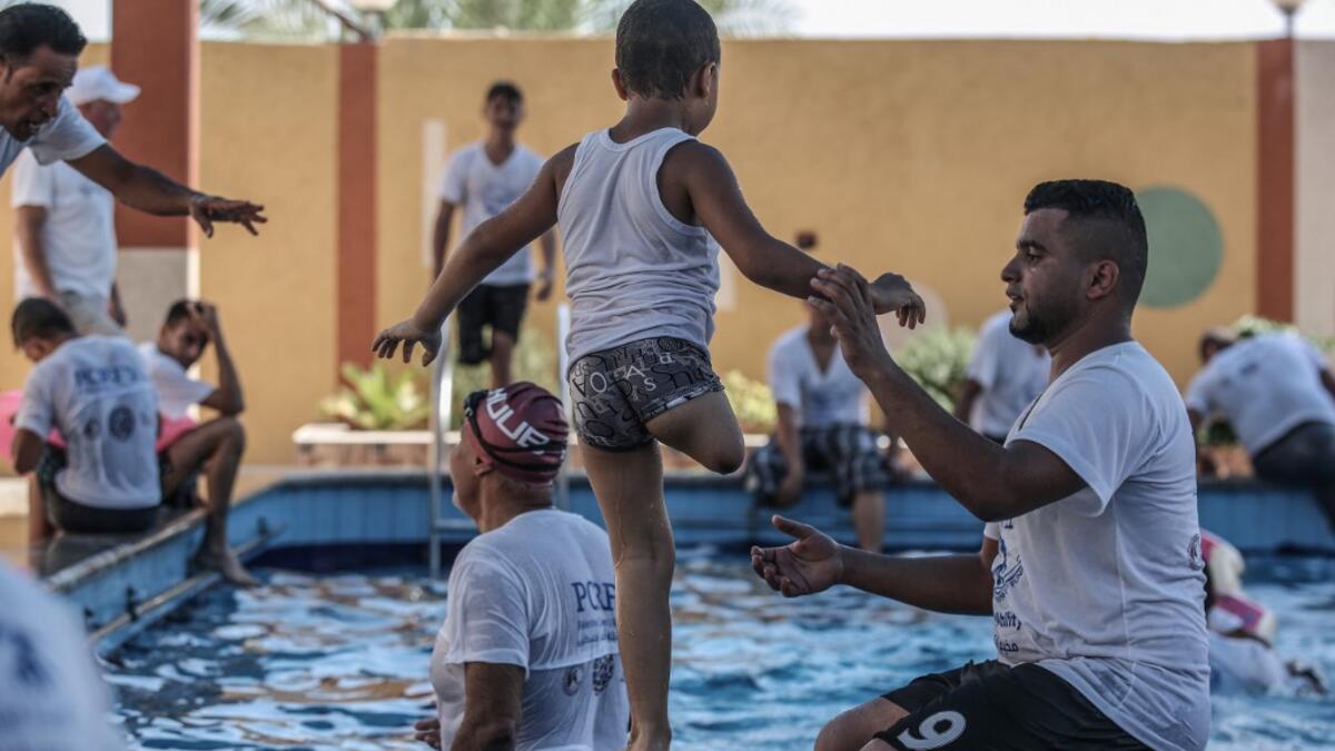 A trainer helps a Palestinian amputee child during a summer camp origanized by the Palestinian Children's Relief Fund (PCRF) in the town of Khan Yunis in the southern Gaza strip on August 3, 2019.  SAID KHATIB / AFP