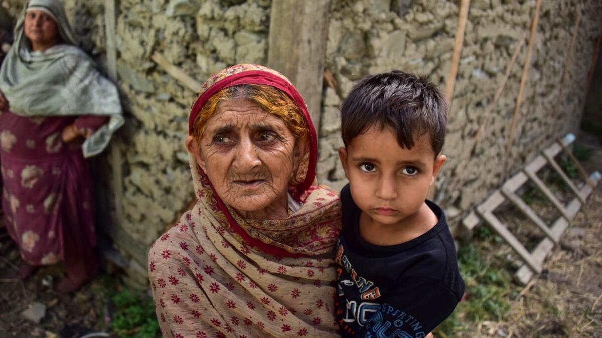 A Kashmiri woman holds a child as she looks on outside her damaged house following recently cross border shelling at the Line of Control, the de facto border between Pakistan and India, in Neelum Valley of Pakistan-administered Kashmir  SAJJAD QAYYUM / AFP