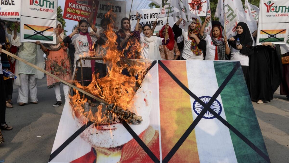 Activists of the 'Youth Forum for Kashmir' group shout slogans as they burn a picture of Indian Prime Minister Narendra Modi and the Indian flag during a protest in Lahore  ARIF ALI / AFP