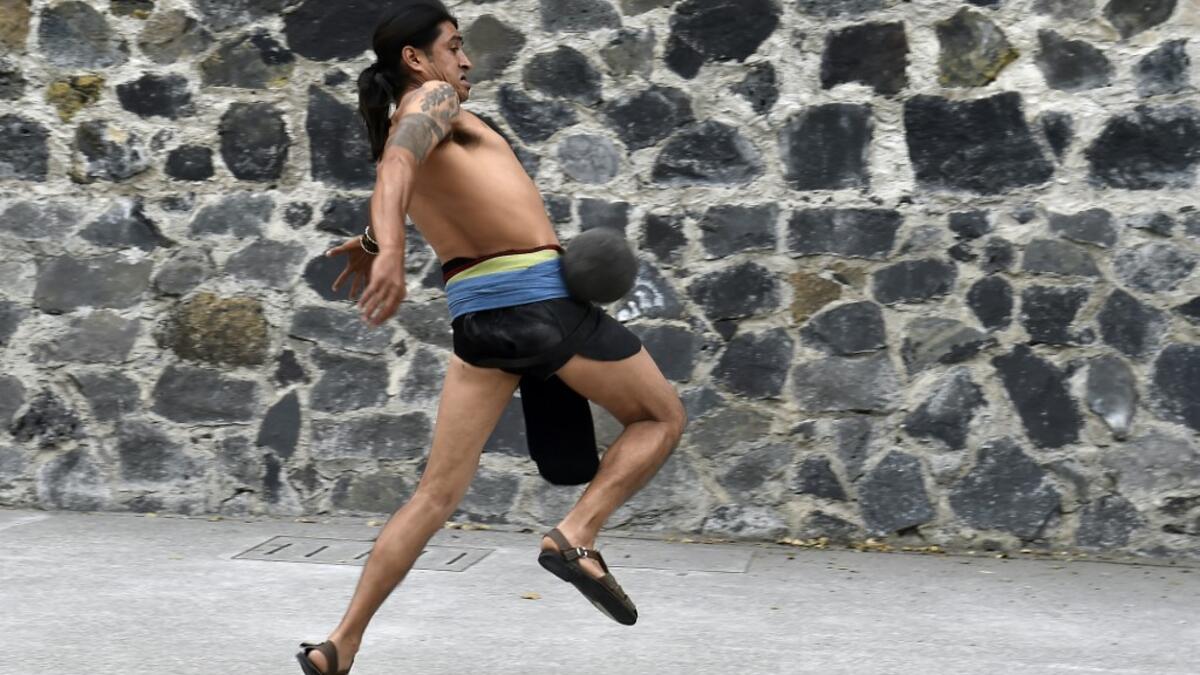 A man plays a pre-Columbian ballgame called "Ulama" -in Nahuatl indigenous language- which rule is to hit a "Ulamaloni" (solid rubber ball) with the hip or shoulder, during a match at the FARO Poniente cultural center in Mexico City on August 21, 2019. ROCIO VAZQUEZ / AFP