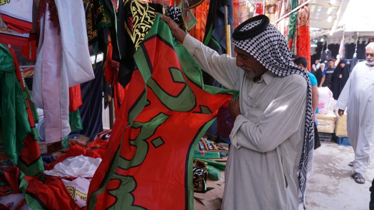 A man holds up a banner reading in Arabic "O Abbas" referring to the Shiite Muslim Imam Abbas ibn Ali, grandson of the prophet Mohammed, sold by a peddlar amidst preparations ahead of the Shiite Muslim religious mourning period of Ashura, in the central Iraqi holy shrine city of Najaf on August 31, 2019.  Haidar HAMDANI / AFP