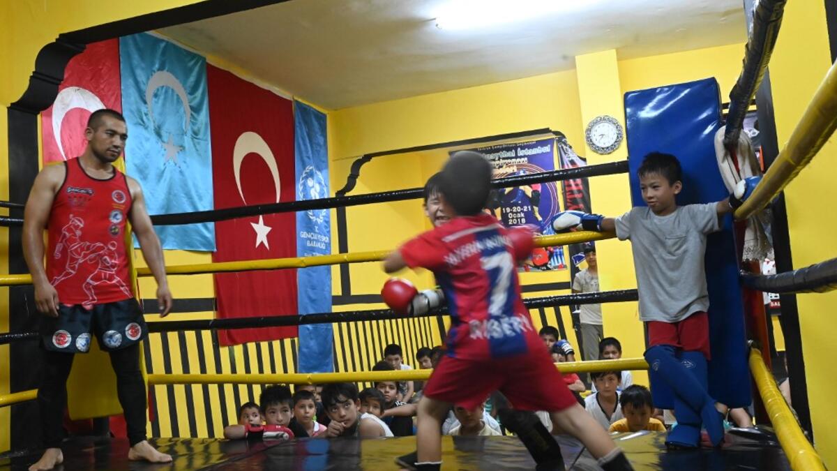 In this photograph taken on August 29, 2019, children from Muslim Uighur minority take part in a training boxing match as a trainer and children watch in Istanbul. BULENT KILIC / AFP