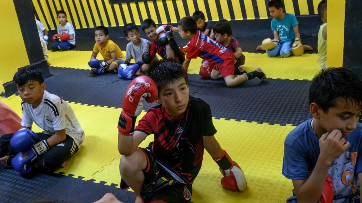 In this photograph taken on August 29, 2019, children from Muslim Uighur minority watch a Muay Thai training session in a boxing academy in Istanbul. BULENT KILIC / AFP